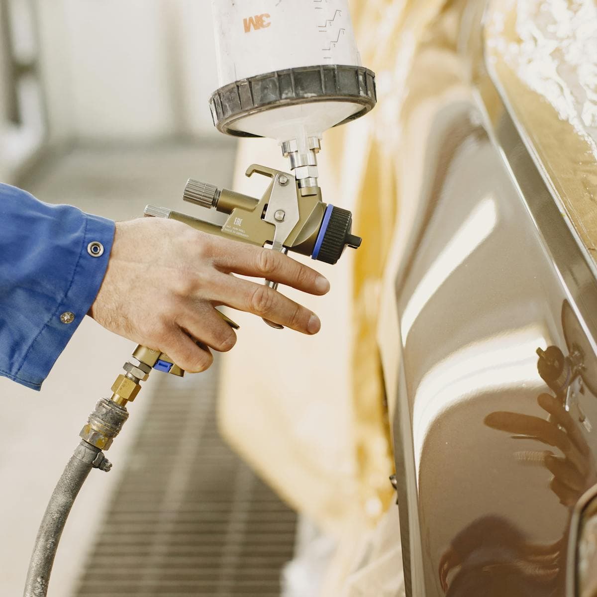 Technician refinishing a panel with a paint spray gun